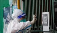 A medical worker in a protective suit collects a swab sample from a resident for nucleic acid testing, outside a closed entrance of a building during lockdown, amid the coronavirus disease (COVID-19) pandemic, in Shanghai, China, May 5, 2022. REUTERS/Aly Song

