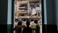 Workers chat at the balcony of a school beside the Saratoga Hotel a day after it suffered an explosion, in Havana, Cuba May 7, 2022. REUTERS/Alexandre Meneghini