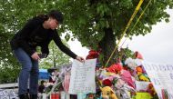 A woman places a sign at a memorial for victims near the scene of a shooting at a Tops supermarket in Buffalo, New York, U.S. May 16, 2022. REUTERS/Brendan McDermid