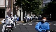 Workers in protective suits ride electric scooters across the street during lockdown, amid the coronavirus disease (COVID-19) pandemic, in Shanghai, China, May 18, 2022. REUTERS/Aly Song