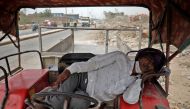 A man sleeps in his tractor parked alongside a road on a hot-weather day on the outskirts of Ahmedabad, India, May 23, 2022. REUTERS/Amit Dave
