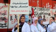 A healthcare worker holds a placard reading 