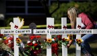 A woman lays a flower next to crosses with the names of victims of a school shooting, at a memorial outside Robb Elementary school, two days after a gunman killed nineteen children and two adults, in Uvalde, Texas, U.S. May 26, 2022. REUTERS/Marco Bello
