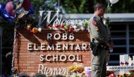 A Texas Department of Public Safety officer stands in front of crosses with the names of victims of a school shooting, at a memorial outside Robb Elementary school, two days after a gunman killed nineteen children and two adults, in Uvalde, Texas, U.S. May 26, 2022. REUTERS/Marco Bello