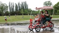 People ride a four-wheeled bike while enjoying at Sun Park on the day of its reopening after the government eased some of the restrictions, amid the coronavirus disease (COVID-19) outbreak in Beijing, China May 29, 2022. REUTERS/Carlos Garcia Rawlins