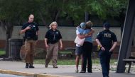 Police officers walk near people embracing at the reunion location, Memorial High School, where they wait to get more information after a shooting at the Saint Francis hospital campus, in Tulsa, Oklahoma, June 1, 2022. Reuters/Michael Noble Jr.