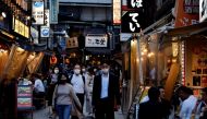 Passersby wearing protective face masks, following an outbreak of the coronavirus disease (COVID-19), walk on the steet at an izakaya pub alley in Tokyo, Japan June 9, 2022. REUTERS/Issei Kato
