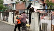 A resident fetches a bag over the fence at a residential compound that is under lockdown, following the coronavirus disease (COVID-19) outbreak, in Chaoyang district of Beijing, China June 12, 2022. REUTERS/Martin Pollard
