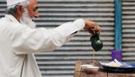 FILE PHOTO: A man fills a cup of tea while having breakfast with paratha flatbread, outside closed shops in Peshawar, Pakistan July 18, 2018. REUTERS/Fayaz Aziz