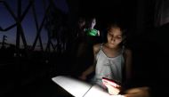 Emily Villega, 10, does her homework using the light of a cell phone at the balcony of her home during a blackout in Guanajay, Cuba June 17, 2022. Reuters/Alexandre Meneghini