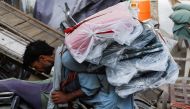 A labourer carries packs of textile fabric to deliver to a nearby shop in a market in Karachi, Pakistan, on June 24, 2022. (Reuters/Akhtar Soomro)