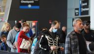 Travellers wearing masks and not wearing masks wait in line at a security checkpoint at Logan International Airport in Boston, Massachusetts, U.S., April 19, 2022. Reuters/Brian Snyder/File Photo
