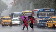Commuters with umbrellas cross a road during heavy rains caused by Cyclone Asani, in Kolkata, India, May 10, 2022. REUTERS/Rupak De Chowdhuri/Files
