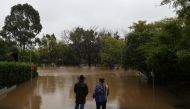 Onlookers stand at the edge of floodwaters on a residential street following heavy rains in the Windsor suburb of Sydney, Australia, July 5, 2022. REUTERS/Loren Elliott