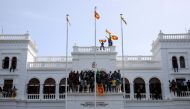 Protestors hold Sri Lankan flags as they stand on top of the office of Sri Lanka's Prime Minister Ranil Wickremesinghe, amid the country's economic crisis, in Colombo, Sri Lanka July 13, 2022. (REUTERS/Adnan Abidi)