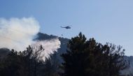 A helicopter drops water to extinguish a wildfire in Datca in Mugla province, Turkey July 14, 2022. REUTERS/Kenan Gurbuz