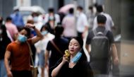 A woman wearing face mask uses a fan as she walks on a street on a hot day, following the coronavirus disease (COVID-19) outbreak in Shanghai, China July 19, 2022. REUTERS/Aly Song/File Photo/File Photo