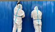 Workers in protective suits set up barriers outside a building, following the coronavirus disease (COVID-19) outbreak, in Shanghai, China June 9, 2022. REUTERS/Andrew Galbraith/

