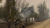 Forensic anthropologists walk into a property to look for human remains in a damaged vehicle as the McKinney Fire burns near Yreka, California, U.S., August 1, 2022. REUTERS/Carlos Barria