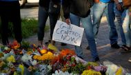A mourner holds a sign advocating for gun control while visiting a memorial for victims of a mass shooting at a Fourth of July parade in the Chicago suburb of Highland Park, Illinois, U.S. July 7, 2022. REUTERS/Cheney Orr


