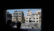 Palestinians look through a damaged window at the rubble of a house destroyed in an Israeli air strike in Gaza City on August 6, 2022. (Reuters/Ibraheem Abu Mustafa)
