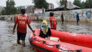 A woman sits in a rubber boat as volunteers pull through a flooded road during the monsoon season in Karachi, Pakistan July 9, 2022. REUTERS/Akhtar Soomro


