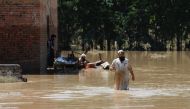 A man wades through flood waters trying to salvage his belongings following rains and floods during the monsoon season in Charsadda, Pakistan August 28, 2022. REUTERS/Fayaz Aziz