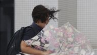 A woman makes her way in strong winds brought by Typhoon Hinnamnor in Naha, Okinawa prefecture, Japan, in this photo taken by Kyodo on September 4, 2022. Kyodo/via Reuters