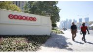 Men look at the logo of Qatar Telecom Ooredoo, formerly Qatar Telecom Qtel, as they walk past the company's head office in Doha March 16, 2013. REUTERS/Fadi Al-Assaad

