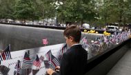 A boy places a flag during a ceremony marking the 21st anniversary of the September 11, 2001 attacks on the World Trade Center at the 9/11 Memorial and Museum in the Manhattan borough of New York City, on September 11, 2022. REUTERS/Amr Alfiky