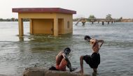 Men who became displaced take a bath amid flood water, following rains and floods during the monsoon season in Sehwan, Pakistan, on September 13, 2022. REUTERS/Akhtar Soomro/File Photo