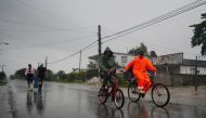 People walk under the rain ahead of the arrival of Hurricane Ian in Coloma, Cuba, September 26, 2022. REUTERS/Alexandre Meneghini