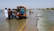 Displaced people stand on a flooded highway, following rains and floods during the monsoon season in Sehwan, Pakistan, on September 16, 2022. (REUTERS/Akhtar Soomro)