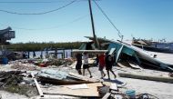 Men carry a wood log in a destroyed marina after Hurricane Ian caused widespread destruction in Fort Myers Beach, Florida, U.S., September 30, 2022. Reuters/Marco Bello