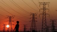 A local walks past electricity pylons during frequent power outages from South African utility Eskom, caused by its aging coal-fired plants, in Orlando, Soweto, South Africa, September 28, 2022. (REUTERS/Siphiwe Sibeko)