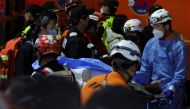 Rescue team members move a body at the scene where dozens of people were injured in a stampede during a Halloween festival in Seoul, South Korea, on October 29, 2022. REUTERS/Kim Hong-ji