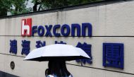 A woman carrying an umbrella walks past the logo of Foxconn outside a company's building in Taipei, Taiwan October 31, 2022. REUTERS/Carlos Garcia Rawlins