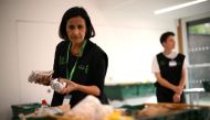 A member of staff sorts through food items inside a foodbank in Hackney, north-east London on October 31, 2022. There were dozens of people on Monday queuing outside the Foodbank in Hackney, an east London district, with a voucher allowing them to obtain a basket containing three days' worth of food. (Photo by Daniel LEAL / AFP)