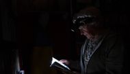 This photograph taken on November 5, 2022, shows physicist Igor Zhuk, 70-years-old, reading a book with help of his headlamp during a power cut in his building, in the north of the Ukrainian capital of Kyiv. (Photo by Sergei SUPINSKY / AFP)