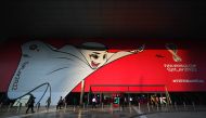 People walk past a poster of Qatar 2022 mascot La’eeb in Doha, yesterday. (AFP)