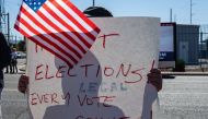A right wing activists stands on the sidewalk with a sign in protest of the election process in front of the Maricopa County Tabulation and election Center on November 12, 2022 in Phoenix, Arizona. (AFP/Jon Cherry)
