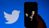 (FILES) In this file photo taken on October 4, 2022, a phone screen displays a photo of Elon Musk with the Twitter logo shown in the background, in Washington, DC. AFP