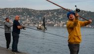Anglers fish on the bank of the Bosphorus as a fishing boat lays its nets in the Marmara sea off the cost of Istanbul, on November 6, 2022. Photo by Yasin Akgul / AFP