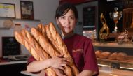 In this file photo taken on May 25, 2017, Japanese baker Mei Narusawa poses while holding baguettes in the Durrenberger bakery in Mertzwiller, eastern France. (Photo by PATRICK HERTZOG / AFP)
