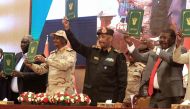 Sudan's Army chief Abdel Fattah al-Burhan (center right) and paramilitary commander Mohamed Hamdan Dagalo (center left) lift documents alongside civilian leaders following the signing of an initial deal aimed at ending a deep crisis caused by last year's military coup, in the capital Khartoum on December 5, 2022. (Photo by ASHRAF SHAZLY / AFP)
 