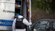 A policeman stands behind a car of the forensic experts during a raid on December 7, 2022 in Berlin. Photo by Tobias Schwarz / AFP
