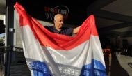 Owner of Sportscafe Munder, Ramesh Jagesar, poses for a picture while holding a flag of the Netherlands in Paramaribo, Suriname, on December 6, 2022. (Photo by Ranu Abhelakh / AFP)