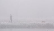 A person with a dog walks through frost and mist alongside a frozen lake in Bushy Park in London, Britain, December 11, 2022. (REUTERS/Maja Smiejkowska)