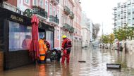 Fire fighters try to open a drain along a flooded street following heavy rains in Lisbon on December 13, 2022. (Photo by FILIPE AMORIM / AFP)