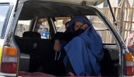 An Afghan woman sits in a parked taxi along the roadside in Kandahar on December 25, 2022. (Photo by Naveed Tanveer / AFP)